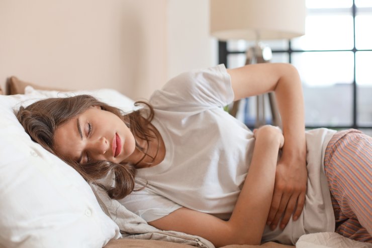 Donna a letto con dolori - AdobeStock