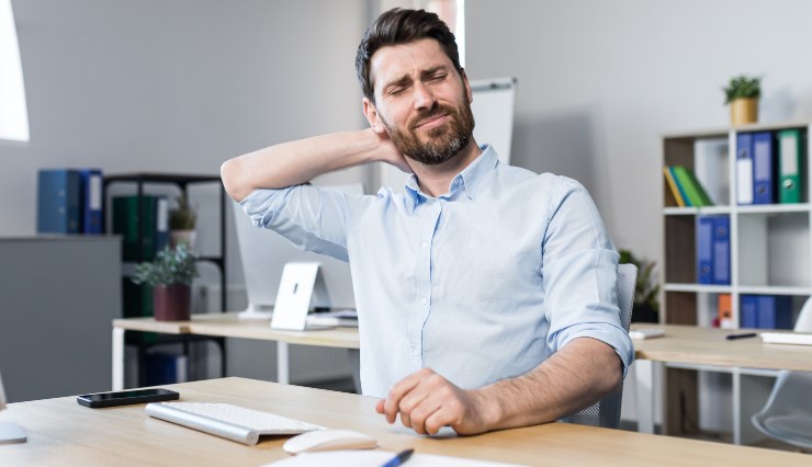 Uomo al lavoro con dolore al collo - Fonte AdobeStock