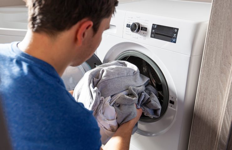 Uomo carica la lavatrice - Fonte AdobeStock